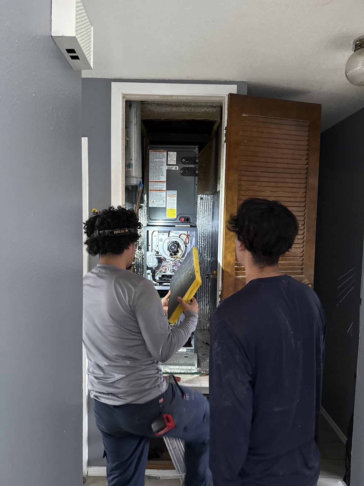 Sons working on furnace installation in a utility closet